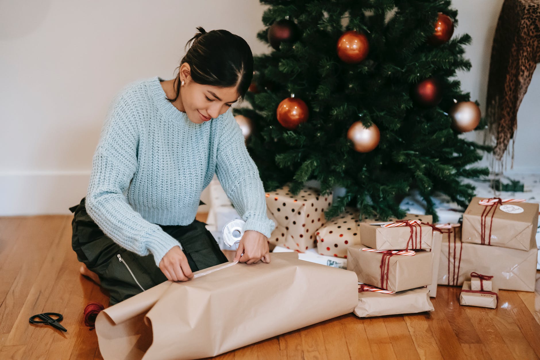 content asian woman wrapping present box near christmas tree